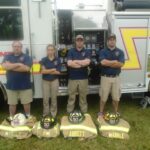 Fire Department Staff Standing by Truck and Gear